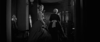Movie still from “The Innocents” (1961), directed by Jack Clayton – Two women dressed in old fashion clothing standing in a room; Medium shot, Low angle