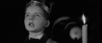 Movie still from “The Innocents” (1961), directed by Jack Clayton – A young boy wearing a crown looking upward; Close Up shot, Low angle