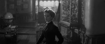 Movie still from “The Innocents” (1961), directed by Jack Clayton – A black and white photo of a woman in a room; Medium shot, Low angle