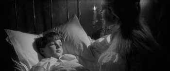 Movie still from “The Innocents” (1961), directed by Jack Clayton – A young boy laying in a bed with a woman; Close Up shot, High angle