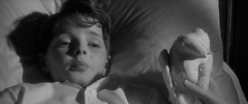 Movie still from “The Innocents” (1961), directed by Jack Clayton – A young boy laying in a bed with a blanket on top of him; Close Up shot, High angle