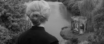 Movie still from “The Innocents” (1961), directed by Jack Clayton – A black and white photo of a woman looking out over a river; Wide shot, High angle
