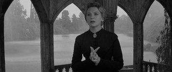 Movie still from “The Innocents” (1961), directed by Jack Clayton – A black and white photo of a woman standing in front of a lake; Medium shot, Low angle