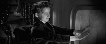 Movie still from “The Innocents” (1961), directed by Jack Clayton – A young man in a suit and tie; Medium shot, High angle