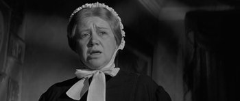 Movie still from “The Innocents” (1961), directed by Jack Clayton – An older woman wearing a black dress and a white hat; Close Up shot, Low angle