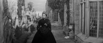 Movie still from “The Innocents” (1961), directed by Jack Clayton – An old photo of a woman dressed in a black dress; Medium shot, Low angle