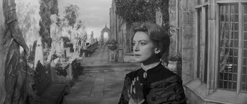 Movie still from “The Innocents” (1961), directed by Jack Clayton – An old black and white photo of a woman praying; Medium shot, Low angle