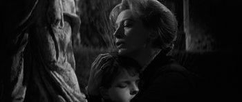 Movie still from “The Innocents” (1961), directed by Jack Clayton – An older woman holding a young boy in her arms; Close Up shot, Low angle
