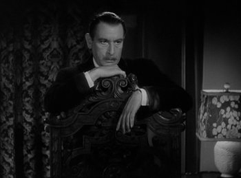 Movie still from “The Invisible Man Returns” (1940), directed by Joe May – A black and white photo of a man sitting in a chair; Medium shot, High angle