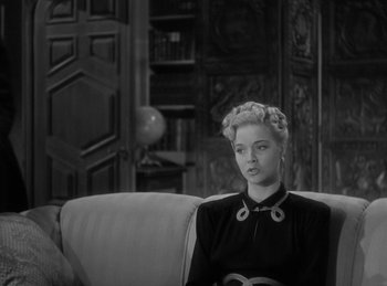 Movie still from “The Invisible Man Returns” (1940), directed by Joe May – A black and white photo of a woman sitting on a couch; Medium shot, High angle