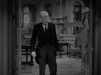 Movie still from “The Invisible Man Returns” (1940), directed by Joe May – A man in a suit and tie standing next to a door way; Medium shot, Over the shoulder angle