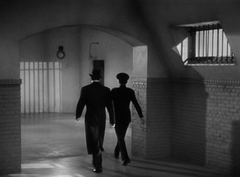 Movie still from “The Invisible Man Returns” (1940), directed by Joe May – A man and a woman walking down a hall way; Wide shot, High angle