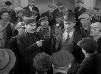 Movie still from “The Invisible Man Returns” (1940), directed by Joe May – A group of men standing next to each other in a room; Medium shot, High angle