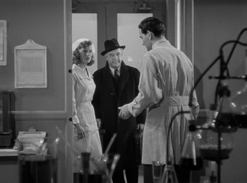Movie still from “The Invisible Man Returns” (1940), directed by Joe May – A group of people standing next to each other in a room; Medium shot, Over the shoulder angle