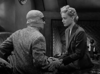 Movie still from “The Invisible Man Returns” (1940), directed by Joe May – A man and a woman sitting in front of each other; Medium shot, Over the shoulder angle