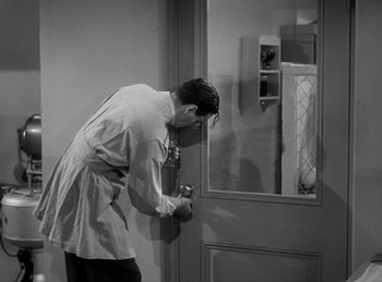 Movie still from “The Invisible Man Returns” (1940), directed by Joe May – A black and white photo of a man leaning against a door; Medium shot, High angle