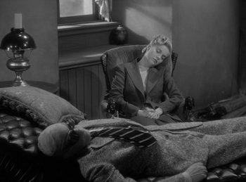 Movie still from “The Invisible Man Returns” (1940), directed by Joe May – A woman sitting in a chair next to a man laying on a bed; Medium shot, High angle