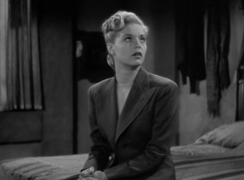 Movie still from “The Invisible Man Returns” (1940), directed by Joe May – A black and white photo of a woman in a suit; Close Up shot, High angle