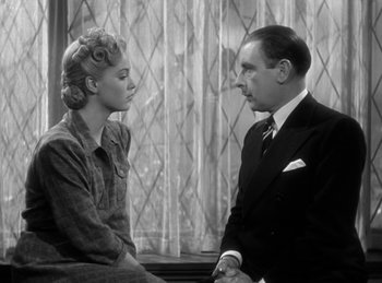 Movie still from “The Invisible Man Returns” (1940), directed by Joe May – An old photo of a man and a woman talking to each other; Medium shot, Low angle