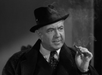 Movie still from “The Invisible Man Returns” (1940), directed by Joe May – An older man wearing a hat and smoking a cigarette; Close Up shot, Low angle