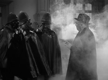 Movie still from “The Invisible Man Returns” (1940), directed by Joe May – A group of men in black hats and hoods; Medium shot, Over the shoulder angle