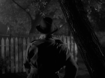 Movie still from “The Invisible Man Returns” (1940), directed by Joe May – A man wearing a hat standing next to a tree; Medium shot, Low angle