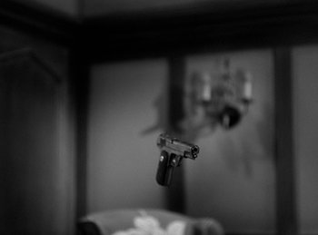 Movie still from “The Invisible Man Returns” (1940), directed by Joe May – A black and white photo of a gun hanging from a wall; Extreme Close Up shot, High angle
