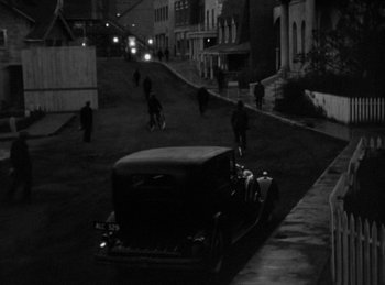 Movie still from “The Invisible Man Returns” (1940), directed by Joe May – An old car parked on the side of the street; Extreme Wide shot, High angle