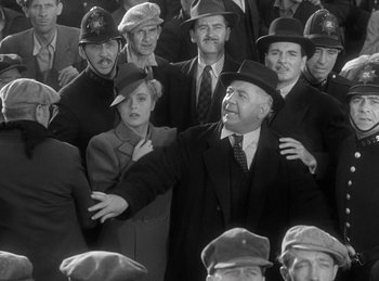 Movie still from “The Invisible Man Returns” (1940), directed by Joe May – A group of men and women wearing hats and suits; Medium shot, High angle