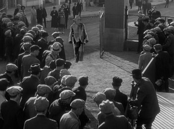Movie still from “The Invisible Man Returns” (1940), directed by Joe May – An old photo of a crowd of people gathered on the sidewalk; Wide shot, High angle