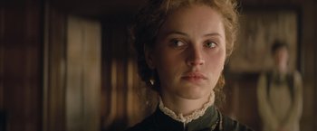 Movie still from “The Invisible Woman” (2013), directed by Ralph Fiennes – A young woman with blonde ringlet hair wearing a black dress; Close Up shot, Over the shoulder angle