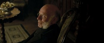 Movie still from “The Invisible Woman” (2013), directed by Ralph Fiennes – An older man with glasses sitting in a chair; Close Up shot, Over the shoulder angle