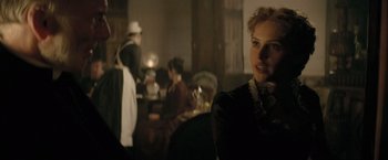 Movie still from “The Invisible Woman” (2013), directed by Ralph Fiennes – A woman in a black dress is in a dark room; Close Up shot, Over the shoulder angle