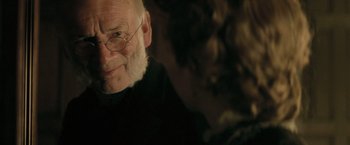 Movie still from “The Invisible Woman” (2013), directed by Ralph Fiennes – An old man with glasses is smiling for the camera; Close Up shot, Over the shoulder angle