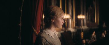 Movie still from “The Invisible Woman” (2013), directed by Ralph Fiennes – A woman with blonde hair wearing a gray dress; Medium shot, Over the shoulder angle