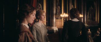 Movie still from “The Invisible Woman” (2013), directed by Ralph Fiennes – Two women are standing next to each other in front of a pillar; Medium shot, Over the shoulder angle