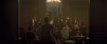 Movie still from “The Invisible Woman” (2013), directed by Ralph Fiennes – A group of people sitting in a room; Wide shot, High angle