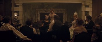 Movie still from “The Invisible Woman” (2013), directed by Ralph Fiennes – A group of people sitting around a room; Wide shot, High angle