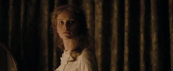 Movie still from “The Invisible Woman” (2013), directed by Ralph Fiennes – A woman in a white dress standing in front of a curtain; Close Up shot, Over the shoulder angle