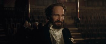 Movie still from “The Invisible Woman” (2013), directed by Ralph Fiennes – A man with a beard and a suit; Close Up shot, Over the shoulder angle