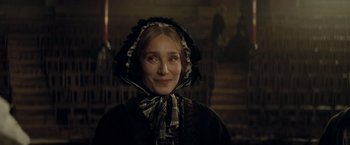 Movie still from “The Invisible Woman” (2013), directed by Ralph Fiennes – A woman in a black and white dress and hat; Close Up shot, Over the shoulder angle