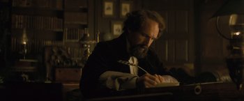 Movie still from “The Invisible Woman” (2013), directed by Ralph Fiennes – A man writing with a quill pen in a dark room; Medium shot, High angle