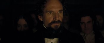 Movie still from “The Invisible Woman” (2013), directed by Ralph Fiennes – A man with a beard wearing a black suit and white shirt; Close Up shot, Over the shoulder angle
