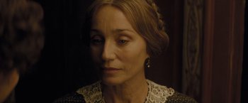 Movie still from “The Invisible Woman” (2013), directed by Ralph Fiennes – An older woman wearing a black and white dress; Close Up shot, Over the shoulder angle