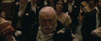 Movie still from “The Invisible Woman” (2013), directed by Ralph Fiennes – An old man with a beard and a flower in his lapel; Close Up shot, Over the shoulder angle