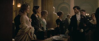 Movie still from “The Invisible Woman” (2013), directed by Ralph Fiennes – A group of people standing around a table; Medium shot, Over the shoulder angle