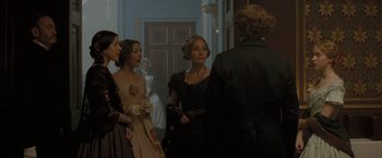 Movie still from “The Invisible Woman” (2013), directed by Ralph Fiennes – A group of people standing in front of a door; Medium shot, Over the shoulder angle