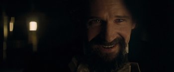 Movie still from “The Invisible Woman” (2013), directed by Ralph Fiennes – A man with a goatee smiling for the camera; Close Up shot, Over the shoulder angle