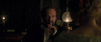 Movie still from “The Invisible Woman” (2013), directed by Ralph Fiennes – A man in a suit and tie smoking a cigarette; Close Up shot, Over the shoulder angle