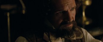 Movie still from “The Invisible Woman” (2013), directed by Ralph Fiennes – A man with a goatee and a beard looking at the camera; Close Up shot, Over the shoulder angle